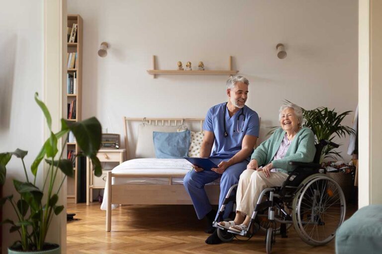 A senior arranging family photos and decorative pillows in a sunlit assisted living apartment.