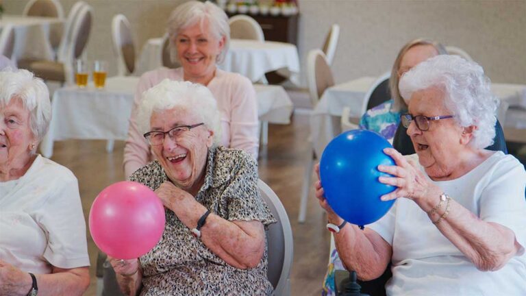 Older adults packing boxes with family and arranging personal items in a bright, comfortable room.