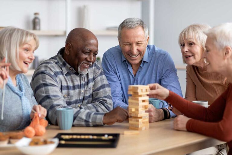 Two older adults and a family member sitting together, looking at a photo album in a cozy home setting.